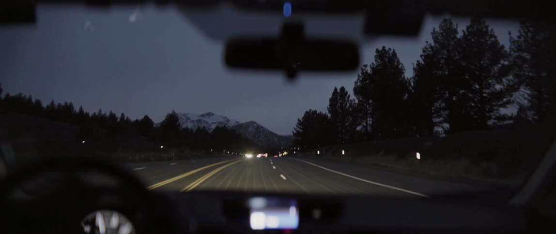 View inside a car as it drives down a road at dawn