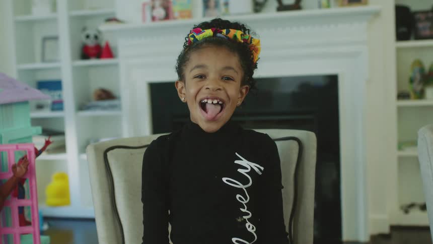 A little girl smiles with an open mouth and her tongue sticking out