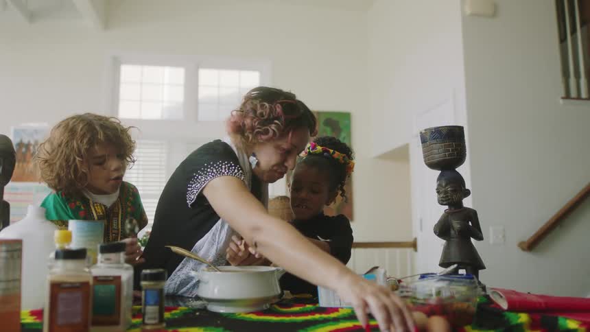A woman and young children mix ingredients into a bowl together