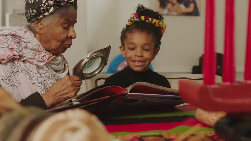 A grandmother is reading to her granddaughter