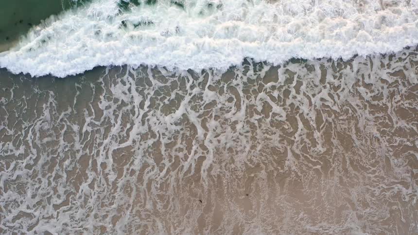 Gentle ocean waves wash onto the beach