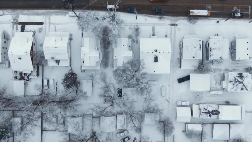 Aerial view of a snow covered neighborhood and traffic on the street