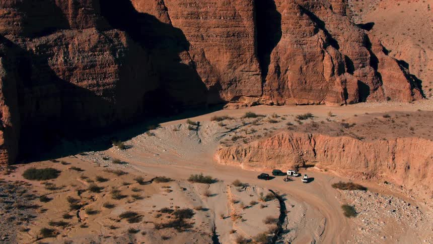 An aerial view of people standing outside their cars at the base of a canyon
