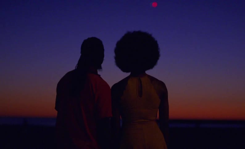 A silhouetted man and woman admiring a sunset while standing side by side