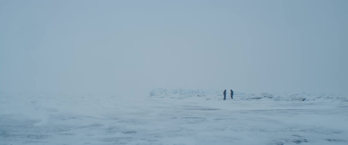 Two people standing in a snowy field on a cold winter day