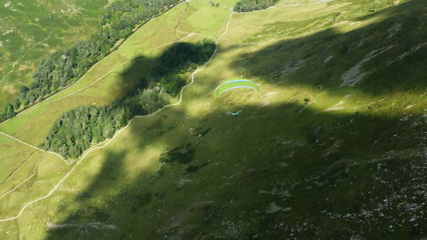 A person is paragliding over the hills