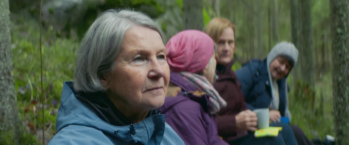 Four women sit and chat in a forest