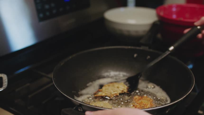 A girl is cooking chicken in a pan