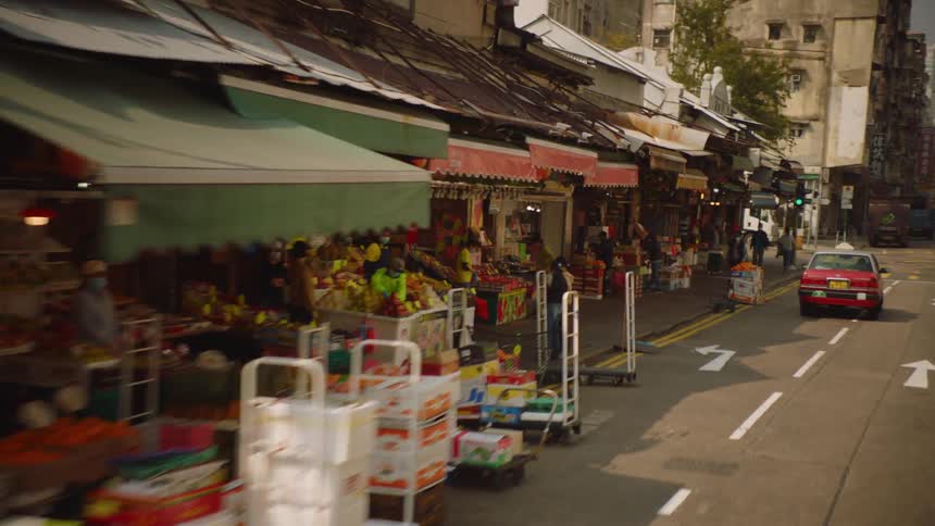 Footage of a street market on the city at daytime filmed from a moving vehicle