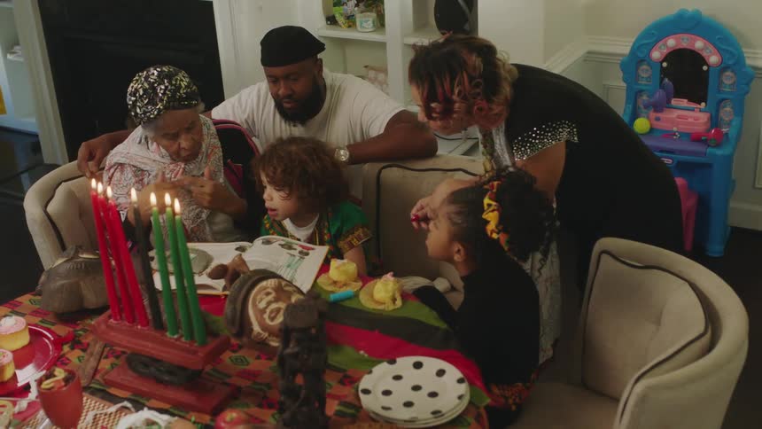 A family reads a book together as they celebrate with lit candles at home