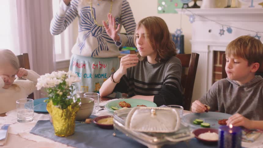 Mother talking to her son and daughters eating in the dinning table at home