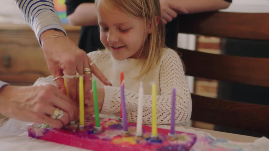 A daughter putting candles into a cake