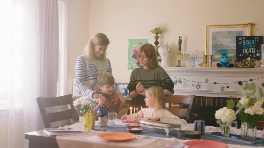 A woman holds onto her sons shoulders as they celebrate with cake and lit candles
