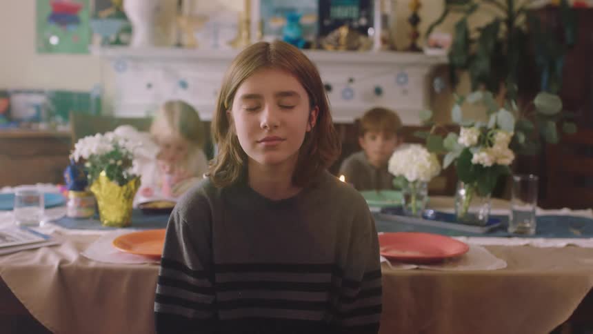 A child sitting at a table in front of siblings