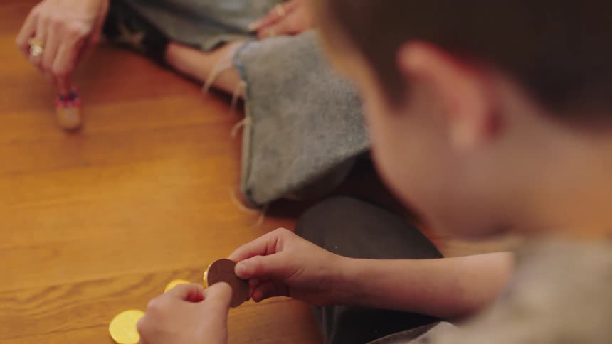 A boy peels the wrapper from a chocolate coin and eats it