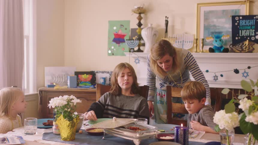 Mother stands watching kids eat then serves food to her son