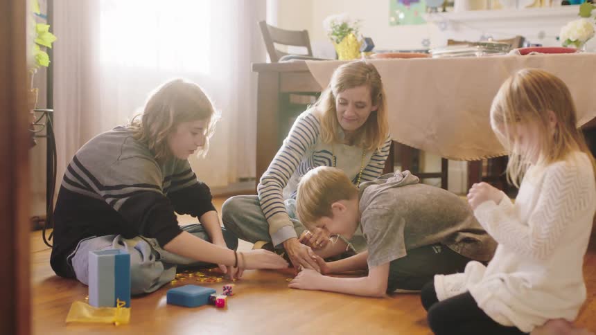 Mother and sons sitting on the floor at home playing with dreidels on hanukkah