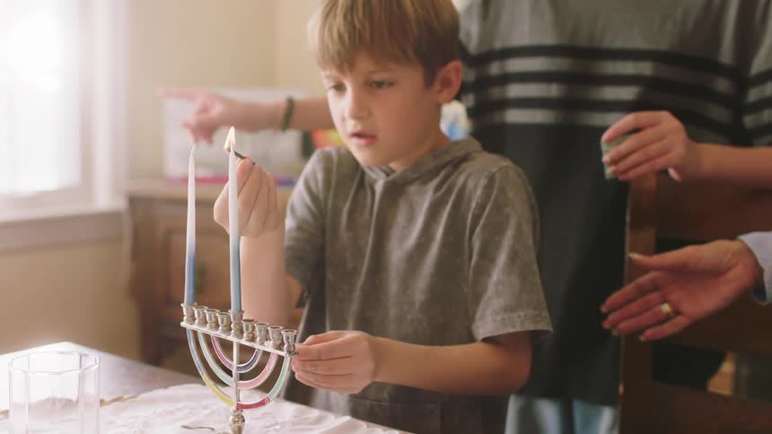 A boy lights a hanukkah candle