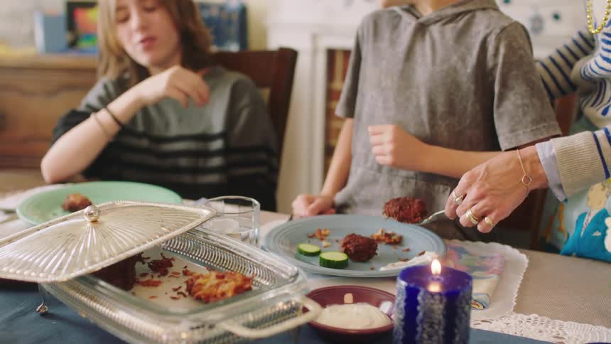 A person serves food on to a childs plate at home
