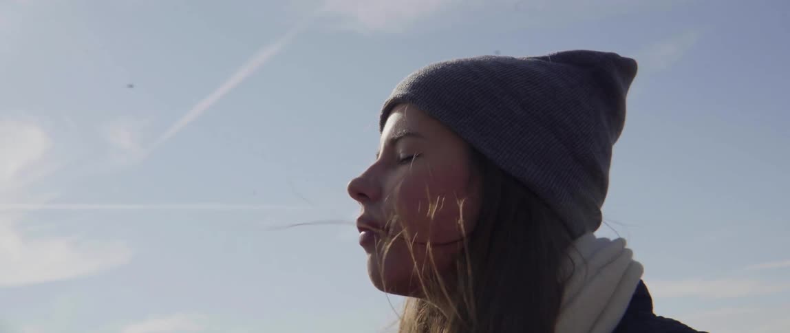 Standing woman feels the sun and breeze on her face