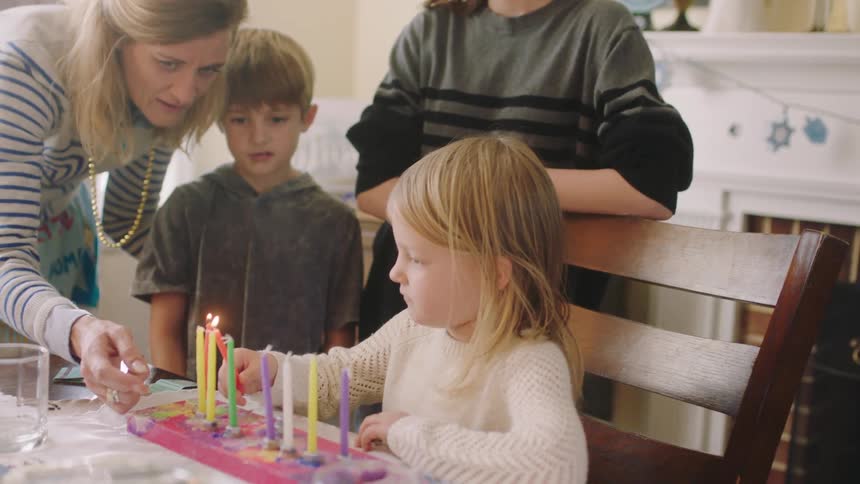 A child lights the candles at the table