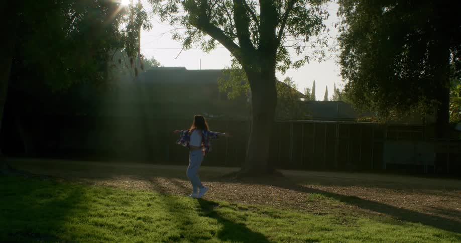 A young woman spins around in her backyard
