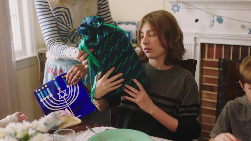 Mother giving her children presents on the dinner table at home