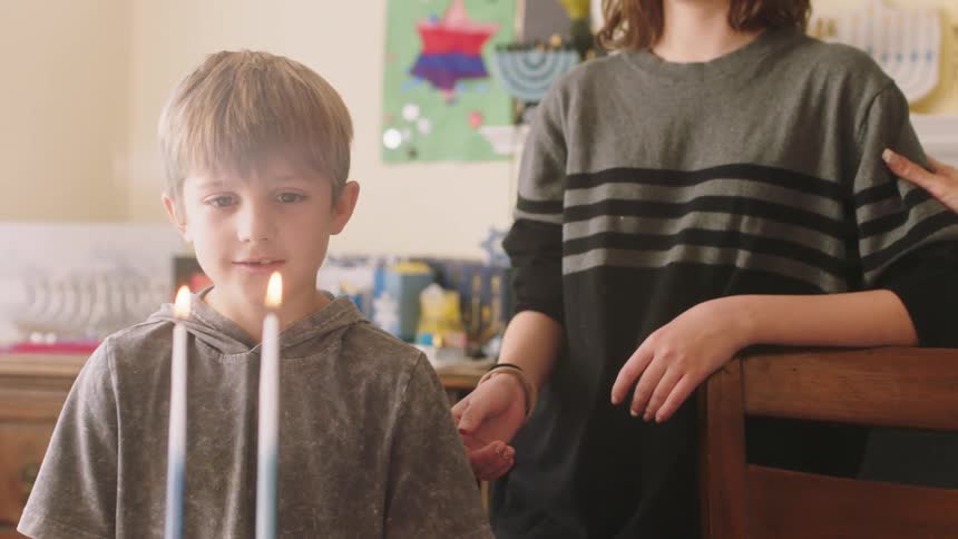 Family stands in front of two burning candles singing