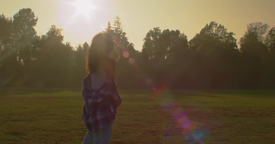 Silhouette of a young female model turning around to look at the camera in front of the sunset