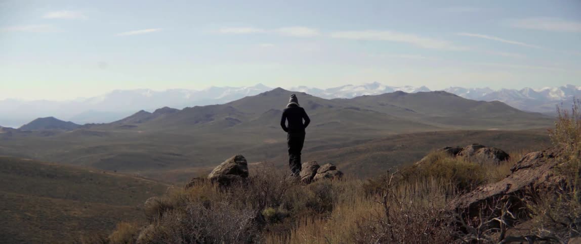 A person is climbing over some rocks before sitting down