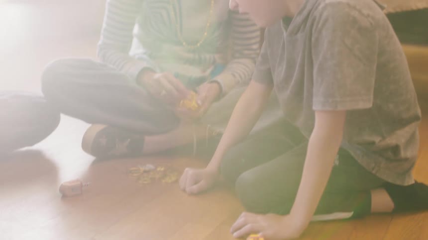 Mother smiles as son laughs after spinning game piece while they sit on dining room floor