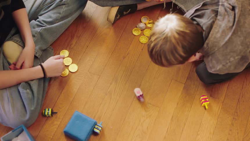 Mother and sons sitting on the floor at home playing with dreidels on hanukkah