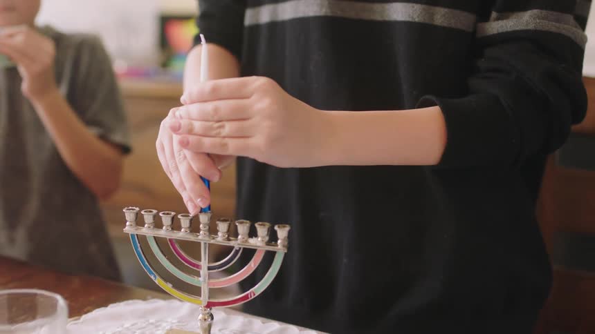 Boy walks over to stand next to table as older sister place candles in candelabra