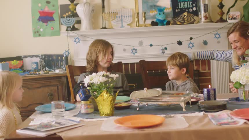 Mother talking to her son and daughters eating in the dinning table at home