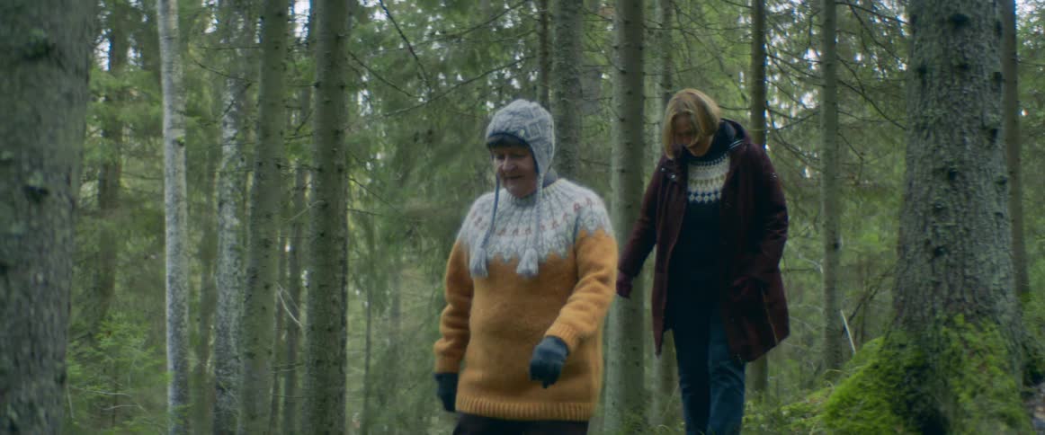 Elderly women with sweaters jeans and gloves walk in the woods on a cold day