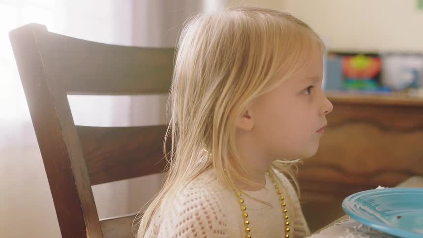 Blonde girl sits at table in front of meal talking