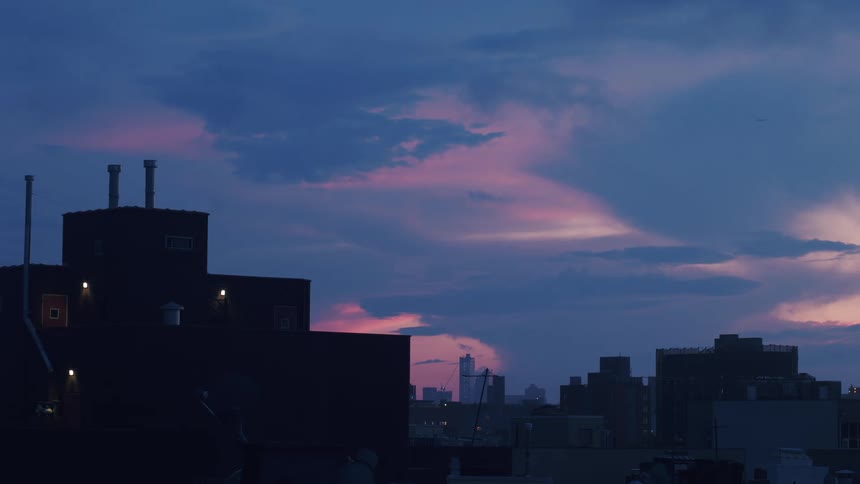 Pink hued clouds move over downtown at dusk