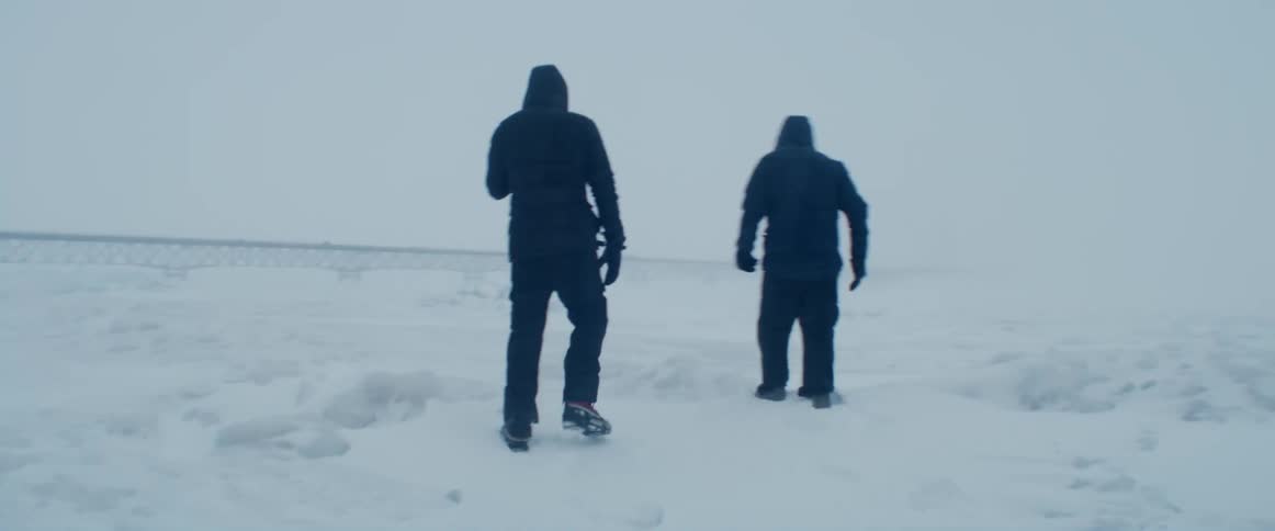 People bundled up for cold walk across snow before climbing down and heading toward water