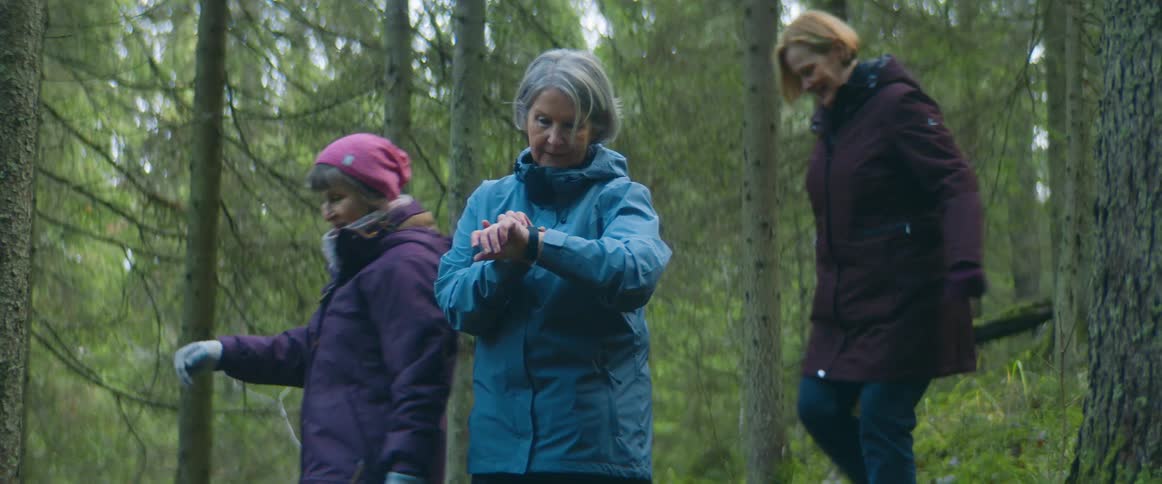 Group of elderly woman hiking on a trail through the forest at daytime