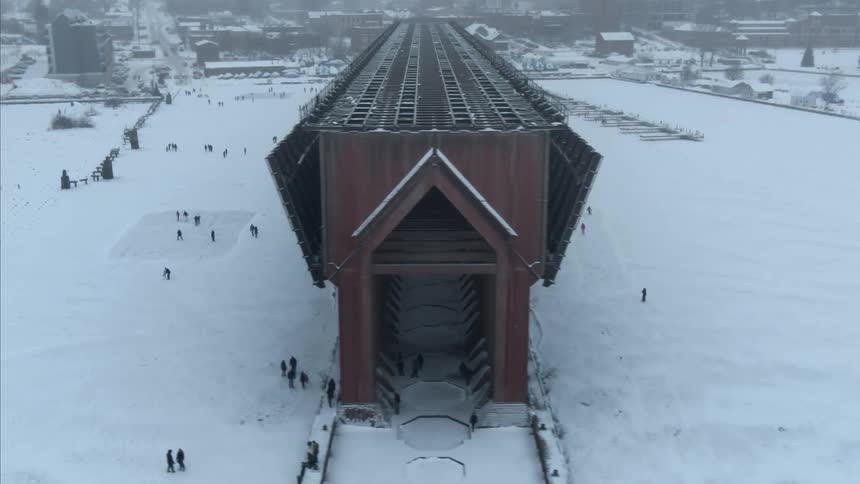 People walk through snow and down long building with side panels raised