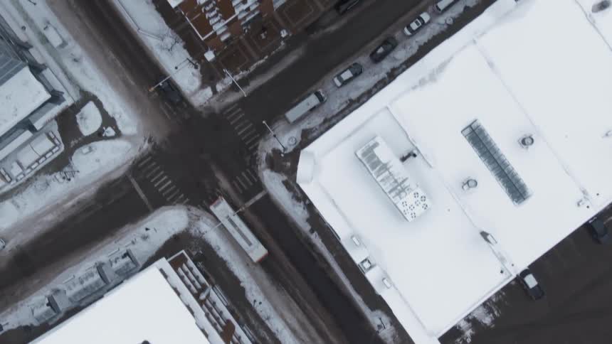 A semi truck drives through a snow covered city neighborhood