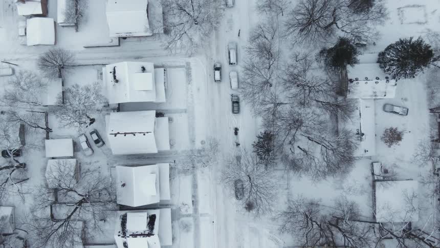 Aerial view of a snow covered neighborhood and an automobile traveling on the street