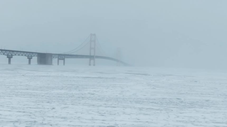 Aerial view of a suspension bridge over the surface of a frozen lake