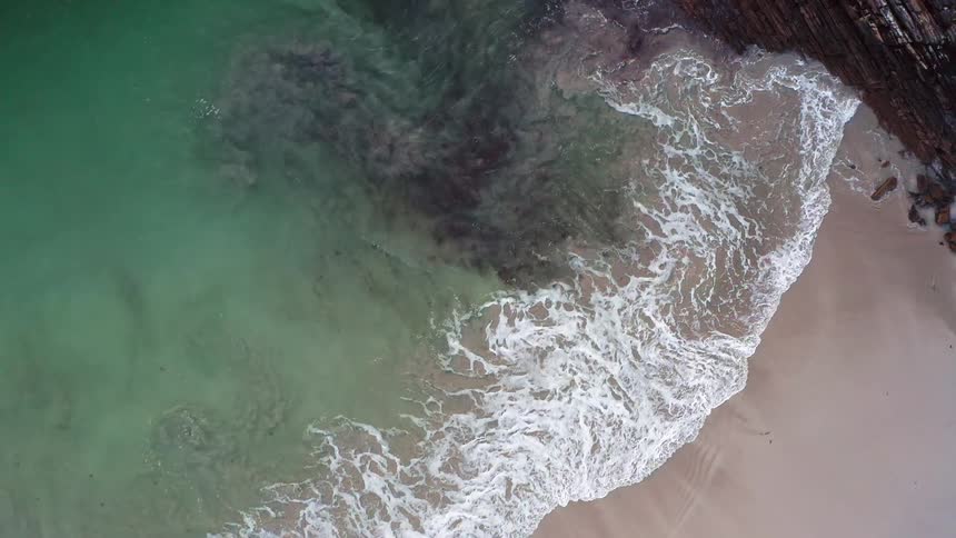 Aerial view of cliff and white sand beach next to the sea