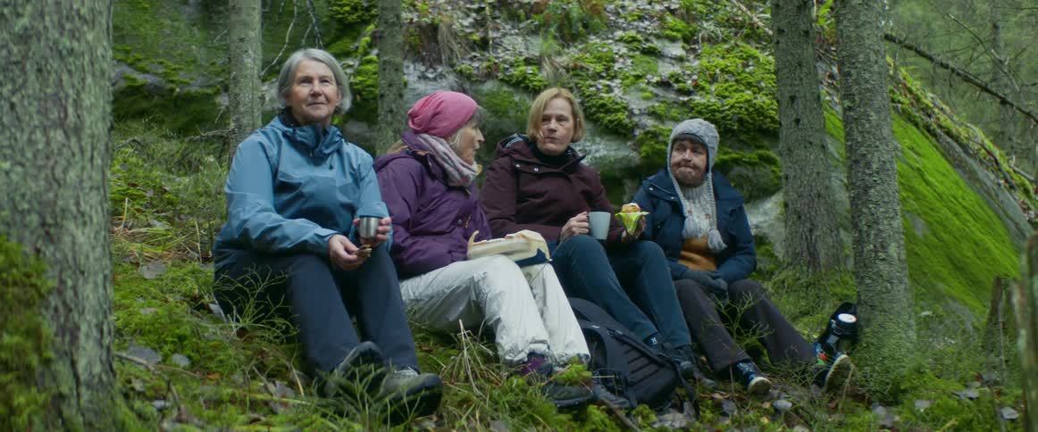 A group of people are sitting in a wooded area
