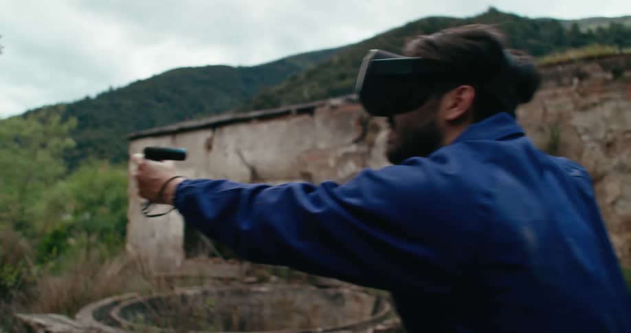 A man jumps around while playing a virtual reality game outside an abandoned building
