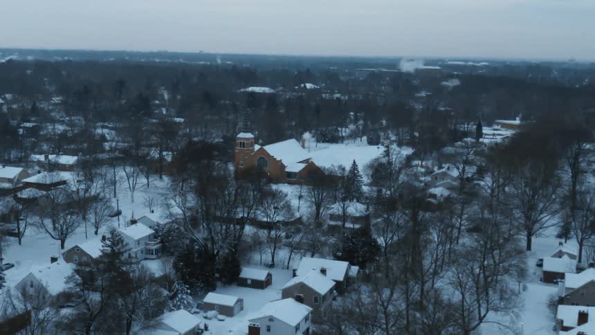Aerial view of snowy town with bare trees
