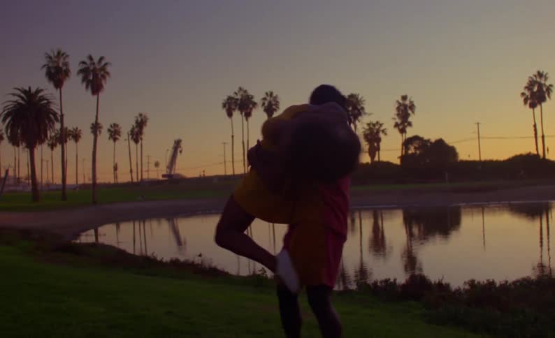 A man spins a woman around as they dance in front of a pond