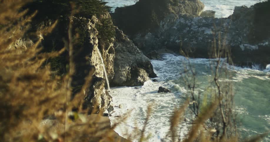Ocean waves gently crashing over the rocks on the coast at sunset