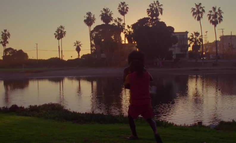 A man and woman dance together outside beside a large pond
